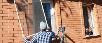 Мужчина снимает москитную сетку с окна частного дома